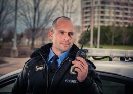 Wincon Campus security guard using walkie-talkie outside mobile patrol car