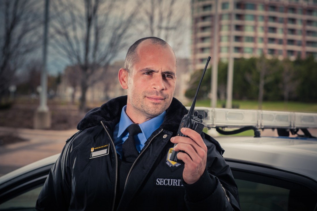 Wincon Campus security guard using walkie-talkie outside mobile patrol car